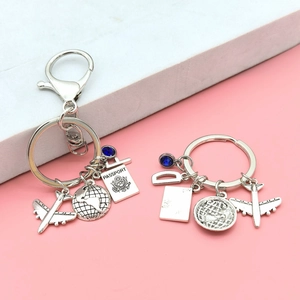 Travel theme metal keychain set featuring airplane passport and globe charms on pink steps