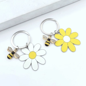 Detail of bee and daisy keychains with yellow petals and crystal accents on metal rings