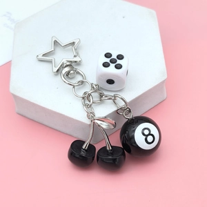 Retro cherry billiard 8 ball and dice keychain with silver star clasp on pink background