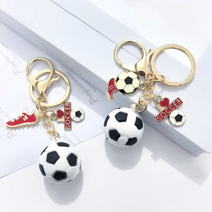 Detail of soccer keychain with black and white ball, red shoe and golden metal ring