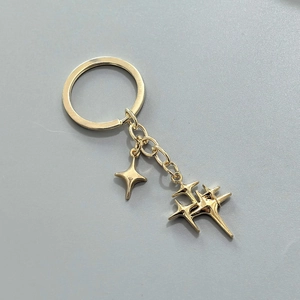 Détail des pendentifs étoiles à quatre branches en métal doré poli et anneau