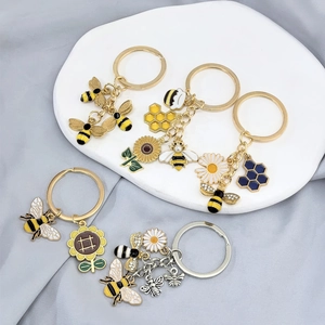 Détails macro des porte-clés émaillés tournesol et abeille avec perles et cristaux
