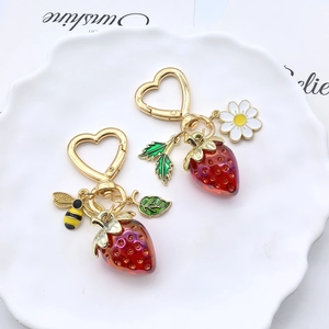 Détail de porte-clés fraise avec fermoir cœur, breloques abeille et marguerite sur plat