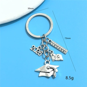 Silver 2026 graduation keychain with mini cap, ruler and book charms on blue background