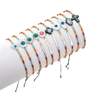 Bohemian Miyuki bead bracelets set with shell cross and evil eye charms on white display