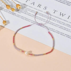 Detalle de pulsera ajustable de cuentas Miyuki con perla blanca central en cordón lila
