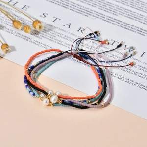 Detalle de cinco pulseras Miyuki hechas a mano ajustables con una perla blanca central