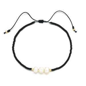 Detail of adjustable black beaded bracelet with three freshwater pearls and golden accents