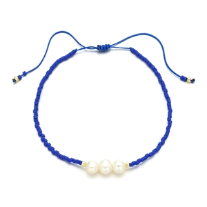 Detail of adjustable blue woven bracelet with white freshwater pearls and golden bead accents