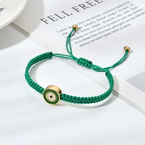 Détail du bracelet mauvais œil vert tissé main avec cordon réglable sur magazine blanc