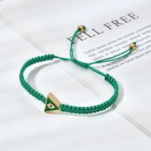 Detail of green braided bracelet with golden triangle evil eye charm and adjustable cord