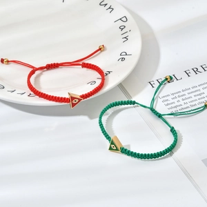 Detailed view of woven bracelets with green and red evil eye triangle charms