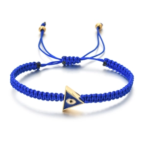 Macro detail of hand-woven blue cord bracelet with gold triangle evil eye charm