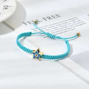 Detail of light blue woven evil eye bracelet with a gold star charm and pull closure