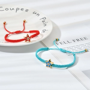 Detail view of woven star evil eye bracelets in red and light blue with gold accents