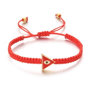 Close-up of red woven evil eye bracelet with triangular gold-rimmed pendant detail