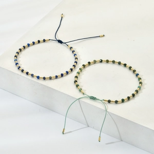 Detail of handmade beaded bracelets with blue and green natural stones and gold spacers