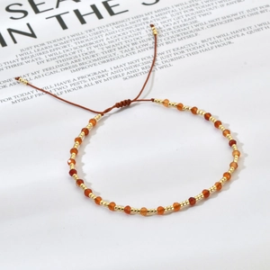 Detailed shot of handmade orange faceted beads and gold spacers on an adjustable cord