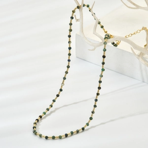Handmade beaded necklace with 2mm green natural stones and gold beads on white branch