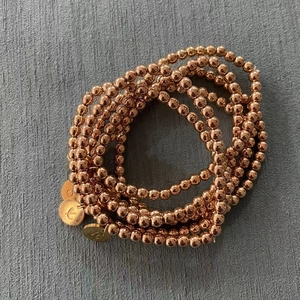 Detailweergave van de roségouden kralenarmbandset met gegraveerde letterbedels