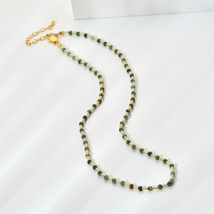 Close-up of handmade beaded necklace with dark green natural stones and gold spacers