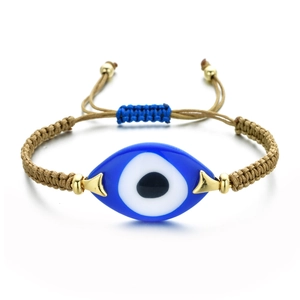 Macro detail of hand-woven Evil Eye bracelet with blue resin bead and adjustable cord