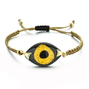 Macro shot of adjustable khaki braided evil eye bracelet with sparkling golden charms