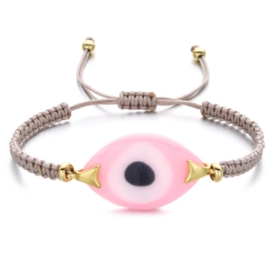 Detailed view of pink evil eye charm on adjustable woven rope bracelet with gold beads