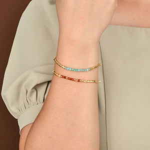Braccialetti in pietre naturali celeste e ambra con dettagli dorati indossati da modella