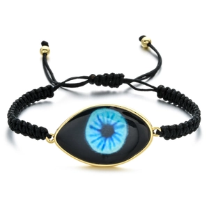 Detail of adjustable black woven rope bracelet featuring a blue evil eye charm and gold beads