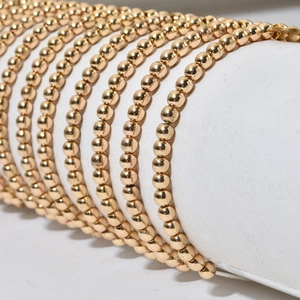 Detail van gelaagde gouden roestvrijstalen kralenarmbanden op een display