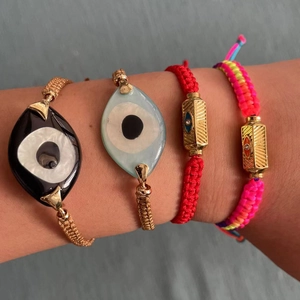 Set of four bohemian Evil Eye woven bracelets with gold charms for women on wrist