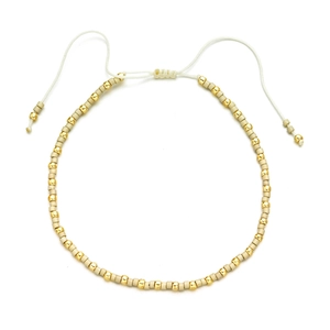 Detail view of Bohemian cream and gold beads with an adjustable white woven cord closure