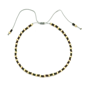 Detail of bohemian handmade beaded bracelet with adjustable grey cord and metallic beads