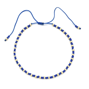 Close-up of bohemian blue beads and gold bead bracelet with adjustable woven cord
