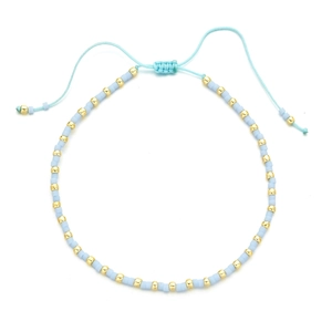 Detail of adjustable blue hand-woven bead bracelet with gold accents and sliding knot