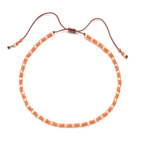 Detail of bohemian handmade beaded bracelet with orange beads and golden metallic accents