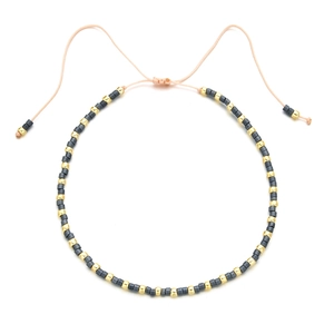 Detail of bohemian gray and gold beads on an adjustable pink braided string bracelet