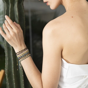 Detail of adjustable bohemian multi-layer stone bead bracelets with gold accents on wrist