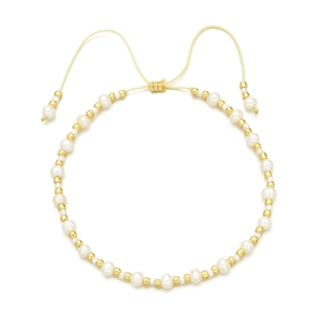 Detail of bohemian woven bracelet with white pearls and gold beads on white backdrop