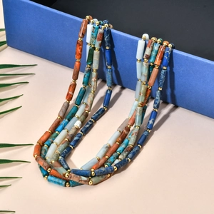 Close-up of bohemian triple-layered necklace with blue stones and gold cylinder beads