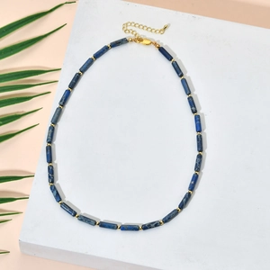 Detailed close-up of blue stone cylinder beads and golden metal spacers on a beaded necklace