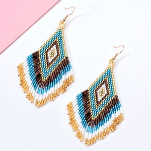 Makroansicht handgefertigter Boho-Perlenohrringe mit blau-goldenen geometrischen Mustern