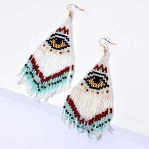 Boucles d'oreilles bohèmes en perles avec motif œil bleu et pompons sur fond blanc pur