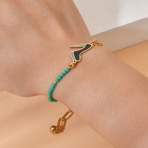 Gold stainless steel bracelet with teal beads and high heel charm on wrist