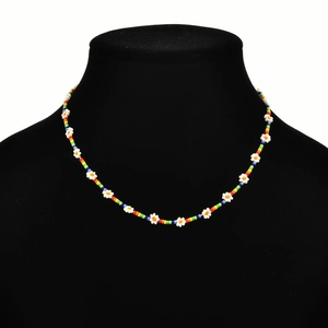 Detail of bohemian rainbow bead necklace with tiny white daisy flower charms on display