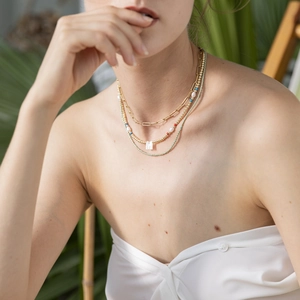 Three-layer bohemian necklace set with gold paperclip chain and M-pendant on a model