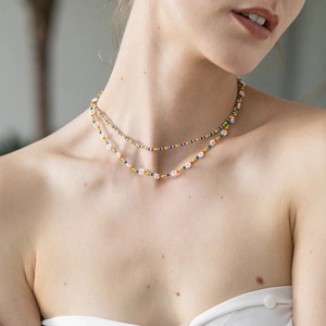 Close-up of double-layer bohemian rainbow seed bead necklace with white daisy flower charms