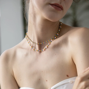 Detail view of double-layer bohemian necklace with rainbow beads and white daisy flowers
