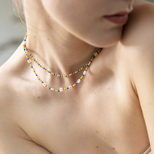 Close-up of bohemian double-layered rainbow bead necklace with white daisy floral accents